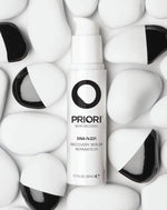 PRIORI DNA Recovery Face Serum Product amongst white and black rocks